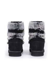 Schwarze Knöchelstiefel mit einem Kunstfellkragen, strukturiertem Stoff und einer niedrigen Gummisohle. Merkmale sind ein weiches, plüschiges Obermaterial und doppelte Riemen.
