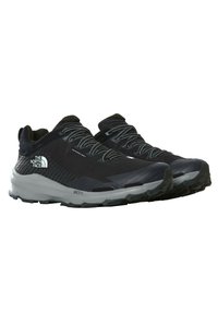 Zapatillas de running negras con una parte superior de malla transpirable, acentos reflectantes, cordones grises y una suela gruesa y texturizada para proporcionar tracción.