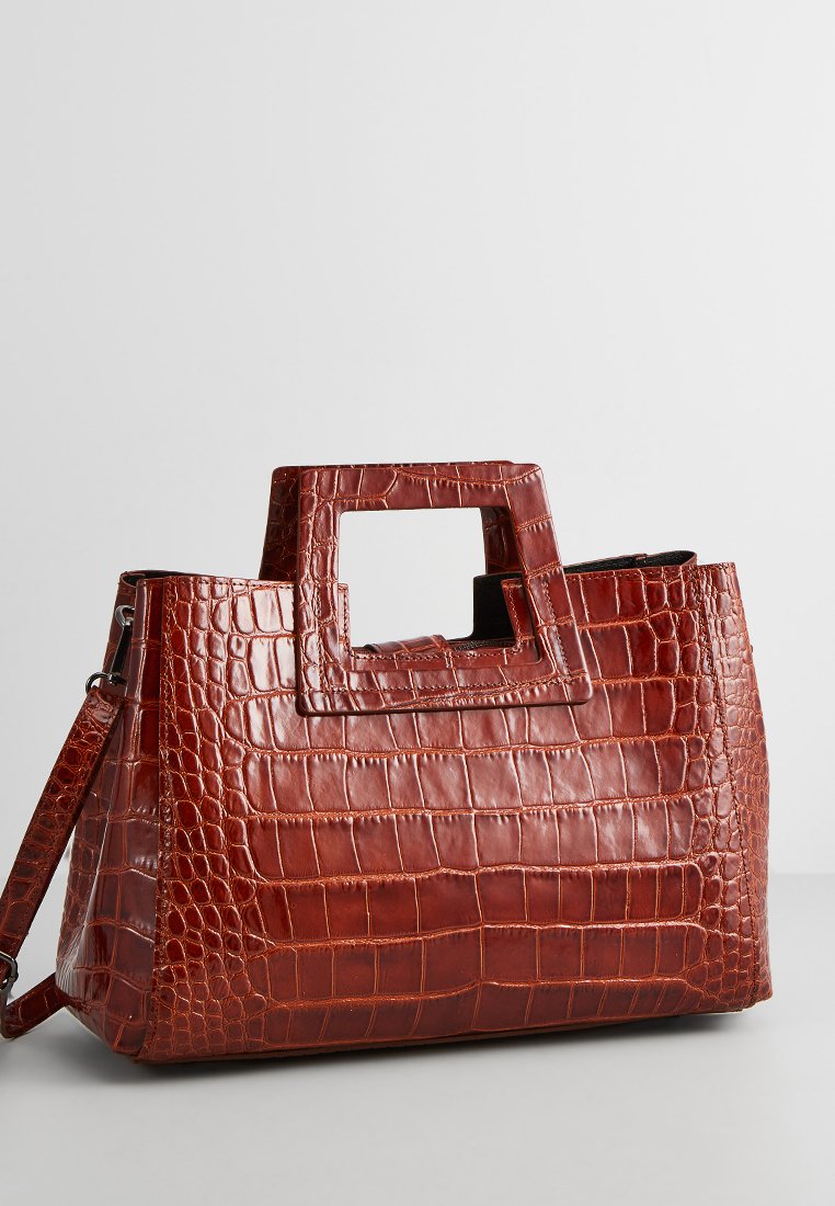 Sac à main en cuir gaufré crocodile marron avec une poignée carrée, une bandoulière amovible et une forme structurée. Texture lisse avec des accents marquants.