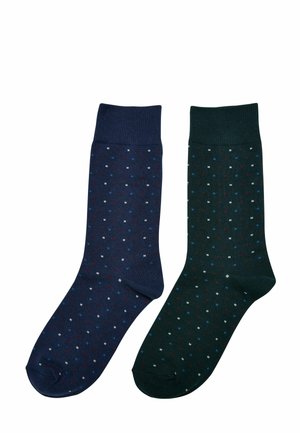 Zwei Paar Baumwollsocken: ein Paar in Marineblau mit kleinen roten, weißen und blauen Punkten, und ein Paar in Dunkelgrün mit ähnlichem Punktenmuster und Farbanordnung.