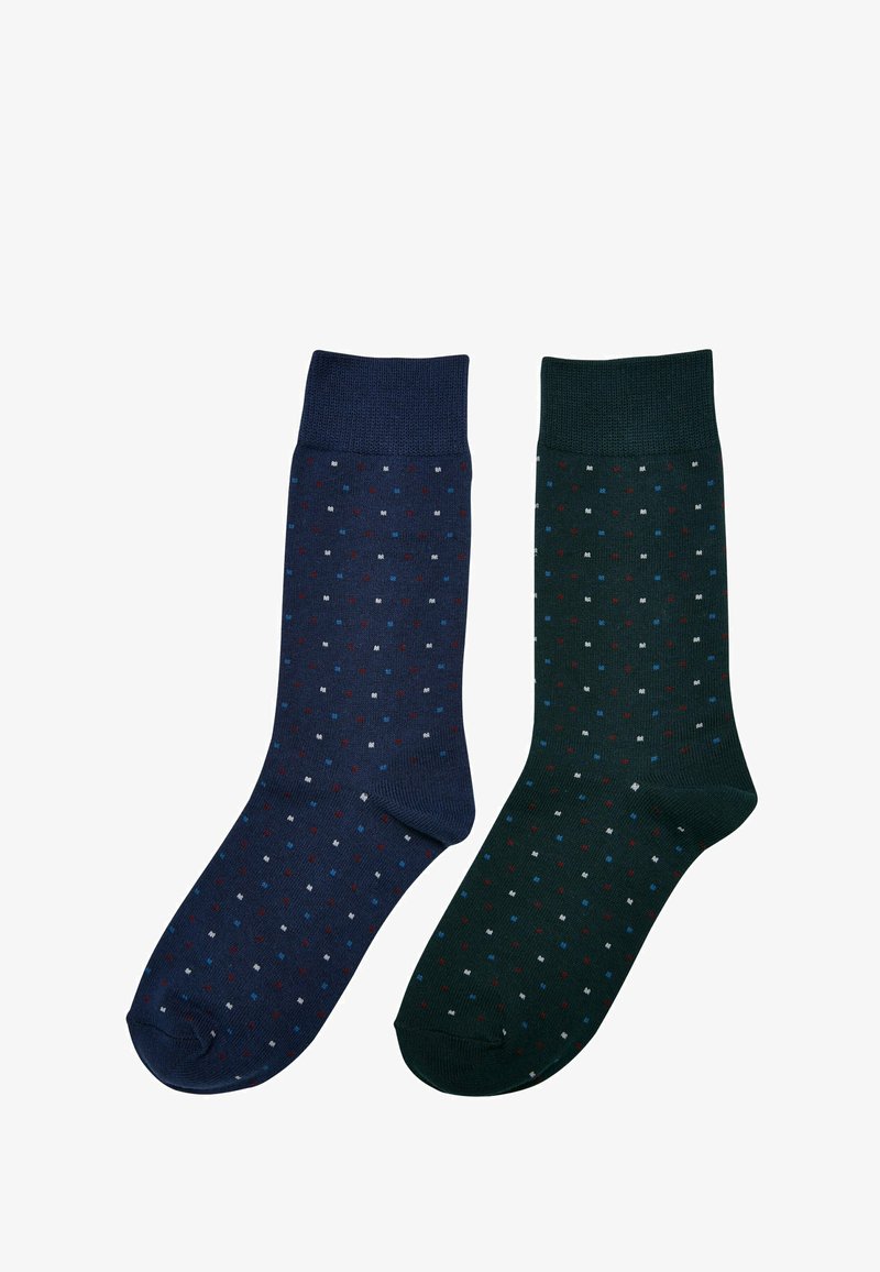 Dos pares de calcetines de algodón: uno en azul marino con pequeños puntos rojos, blancos y azules, y otro en verde oscuro con un patrón de puntos similar y disposición de colores.