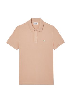 Jasno brzoskwiniowa polo wykonana z bawełny, z klasycznym kołnierzykiem, krótkimi rękawami oraz małym zielonym logo krokodyla Lacoste na piersi.
