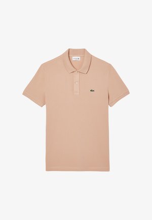 Polo shirt de melocotón claro hecho de algodón, con cuello clásico, mangas cortas y un pequeño logo de cocodrilo verde de Lacoste en el pecho.