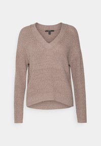 Sweter z dekoltem w serek w jasnym brązie, o luźnym kroju, z długimi rękawami, prążkowanymi krawędziami oraz teksturowanym materiałem z delikatnym połyskiem.