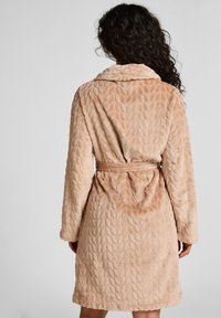 Beige Frottee-Bademantel mit einem Blattmuster, Schalkragen, langen Ärmeln und einem Bindegürtel in der Taille. Weiche Textur, knielanges Design.