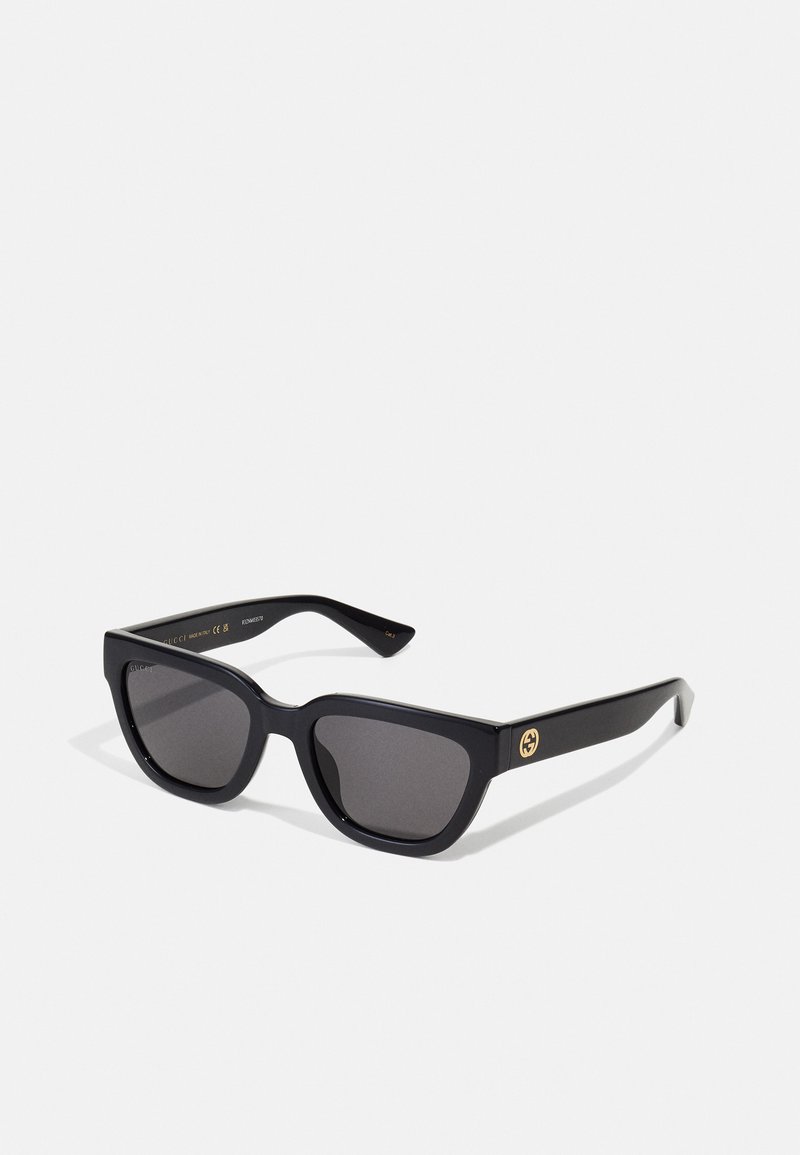 Gafas de sol rectangulares negras con acabado brillante, lentes oscuros y detalle en dorado en las patillas con el logotipo.