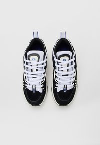 Pair of black and white athletic shoes with white laces, viewed from above on a plain white background.