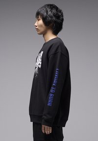 Μαύρο φούτερ με γραφικό σχέδιο στο μπροστινό μέρος και τη φράση «LUXURY TO BURN» σε μπλε χρώμα στο μανίκι. Διαθέτει άνετη γραμμή και ριμπ μανσέτες.