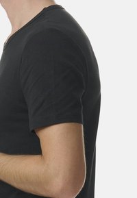 Czarna bawełniana koszulka z krótkim rękawem o dekolcie w serek, z dopasowanym krojem. Gładka faktura i wyraźne linie widoczne z boku.