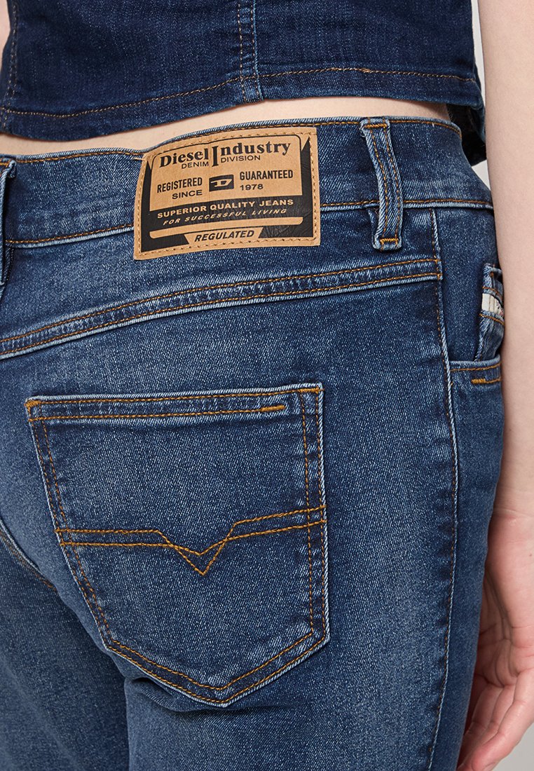 Donkerblauwe denim jeans met zichtbare stiksels, een leren label met merknaam op de tailleband en een standaard achterzakontwerp met een hoekig motief.