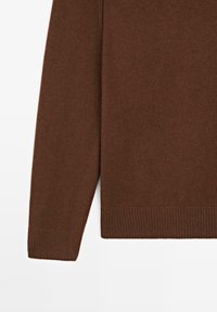 Brauner gestrickter Pullover mit langen Ärmeln, gerippten Bündchen und strukturierter Oberfläche. Das Design ist schlicht und legt den Fokus auf Wärme und Komfort.