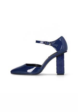 Escarpin Mary Jane en cuir verni bleu marine, bout pointu, bride à la cheville et talon bloc avec motif géométrique embossé.