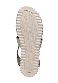 Semelle de sandale avec une surface beige texturée arborant un motif en relief et une marque en embossage, montrant un design plat et segmenté pour l'adhérence.