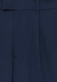 Námořnické modré kalhoty vyrobené z texturované tkaniny, které mají jednu boční kapsu a přiléhající pas s poutky na opasek.