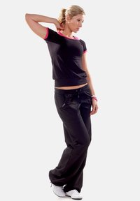 Black short-sleeve top with pink accents, paired with loose black pants. Wearing white sneakers. Simple, casual athletic wear.