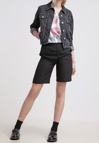 Czarna dżinsowa kurtka na kwiecistym topie, w zestawie z dopasowanymi czarnymi szortami i skórzanymi butami. Ubranie charakteryzuje się casualowym stylem z czystymi liniami.