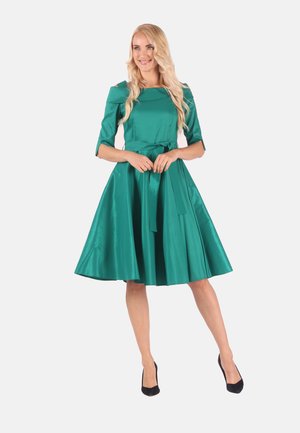 Türkisfarbenes Satin-Kleid mit tailliertem Oberteil, Rundhalsausschnitt und Gürtel in der Taille, das in einen knielangen, plissierten Rock mündet. Kurze Ärmel.
