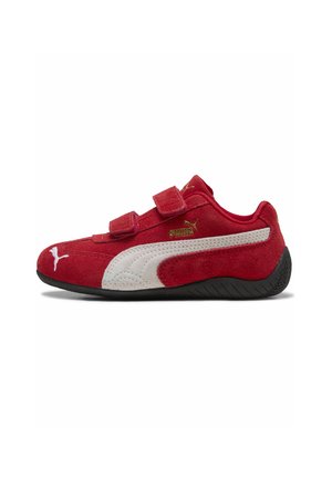 Rød Puma-sneaker med hvid stribe, sort sål og to velcrolukninger, vist fra indersiden mod hvid baggrund.