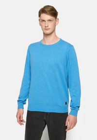 Pulover albastru cu guler rotund, dintr-un tricot texturat, cu mâneci lungi și manșete și tiv cu striații. Etichetă logo neagră în colțul stâng jos.