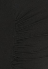 Černá elastická tkanina s nabíranou strukturou, vykazující jemné vlnění na povrchu. Měkký, pružný materiál, navržený pro těsný střih.