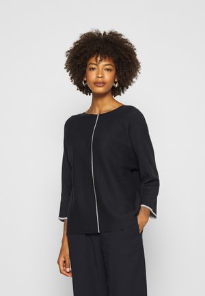 Schwarzes Strickoberteil mit rundem Ausschnitt, featuring eine zentrale weiße Naht und Dreiviertelärmel mit einem weißen Saum. Glatte Textur.