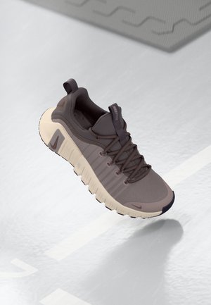 Nike Free sneakers in grijs en beige, met een getextureerde bovenkant, flexibele zool, vetersysteem en een lus aan de hiel voor gemakkelijk aantrekken.