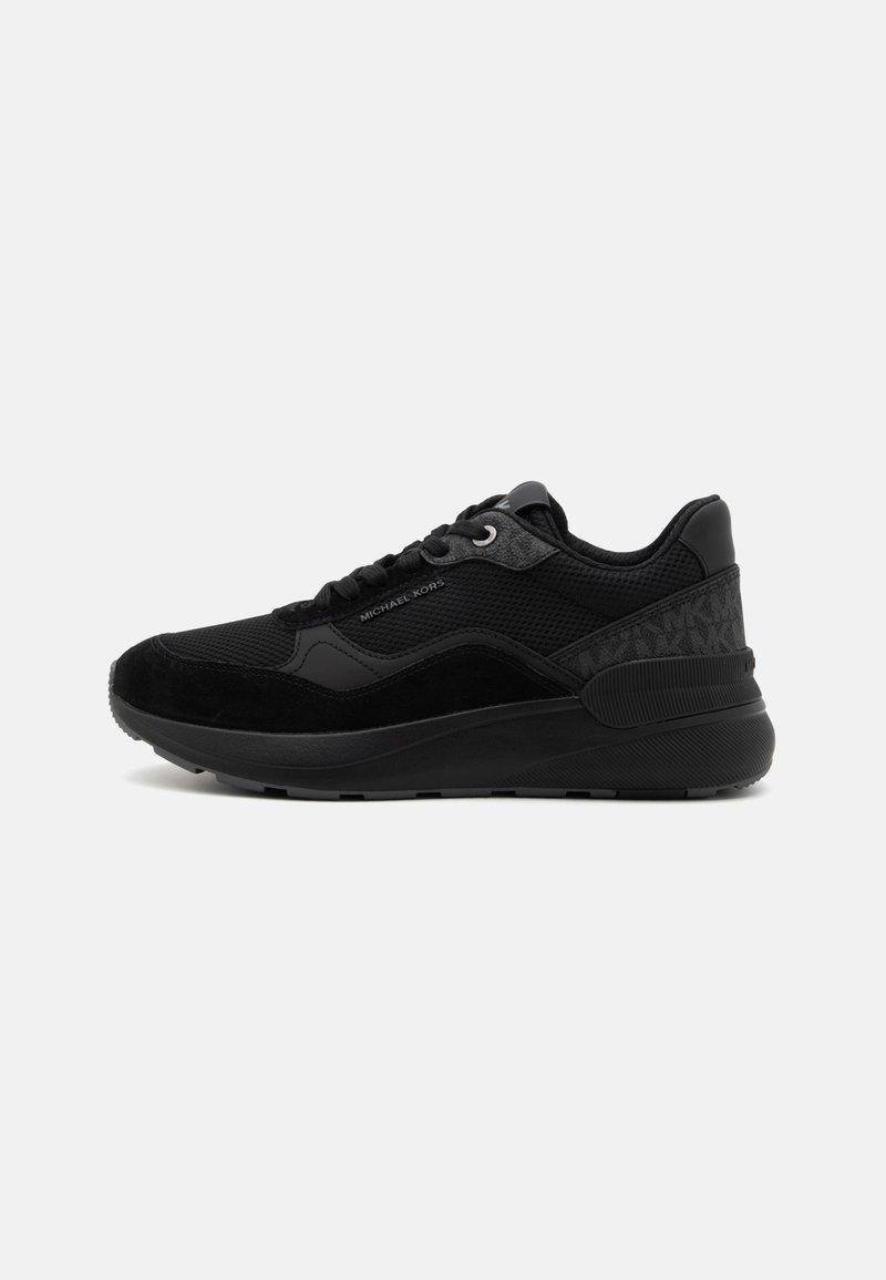 Black athletic shoe featuring a mix of mesh and suede materials, round toe, laces, embossed accents, and a textured midsole.