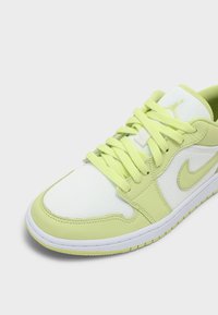 Basket basse avec superpositions vert clair, base en mesh blanc, lacets vert clair, swoosh Nike et logo Jordan sur la languette.