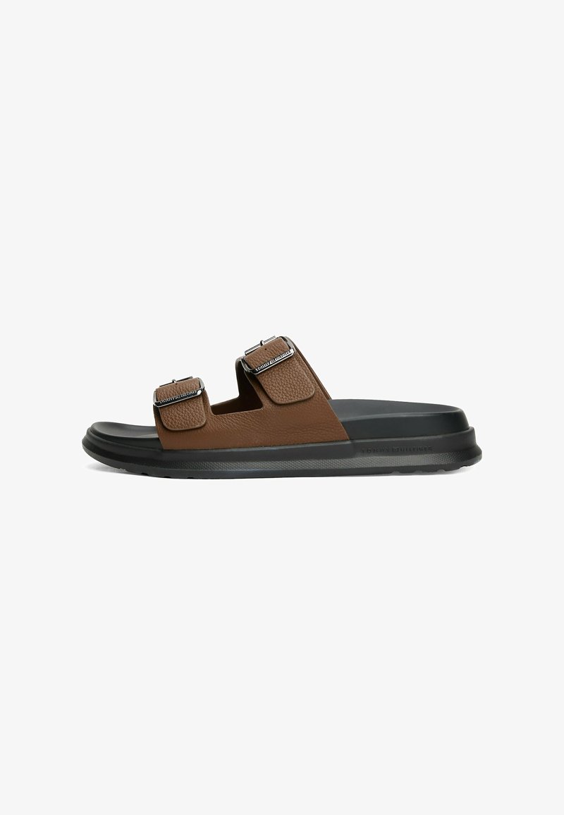 Bruine leren sandalen met twee verstelbare banden, metalen gespen, een gestructureerde bovenkant en een dikke zwarte rubberen zool.