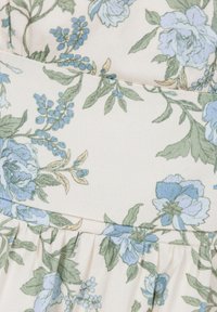 Bloemenprintstof met blauwe en groene bloemen op een crèmekleurige achtergrond, voorzien van gathered textuur en plooien aan de onderkant.