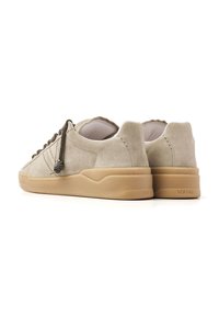 Beige suede sneakers with a textured finish, round toe, and rubber outsole. Features dark laces and stitching accents.