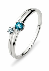 Sølv ring med to runde, facetslebne ædelsten—en teal og en lys blå—sat i et design med fire klør, med en poleret finish.