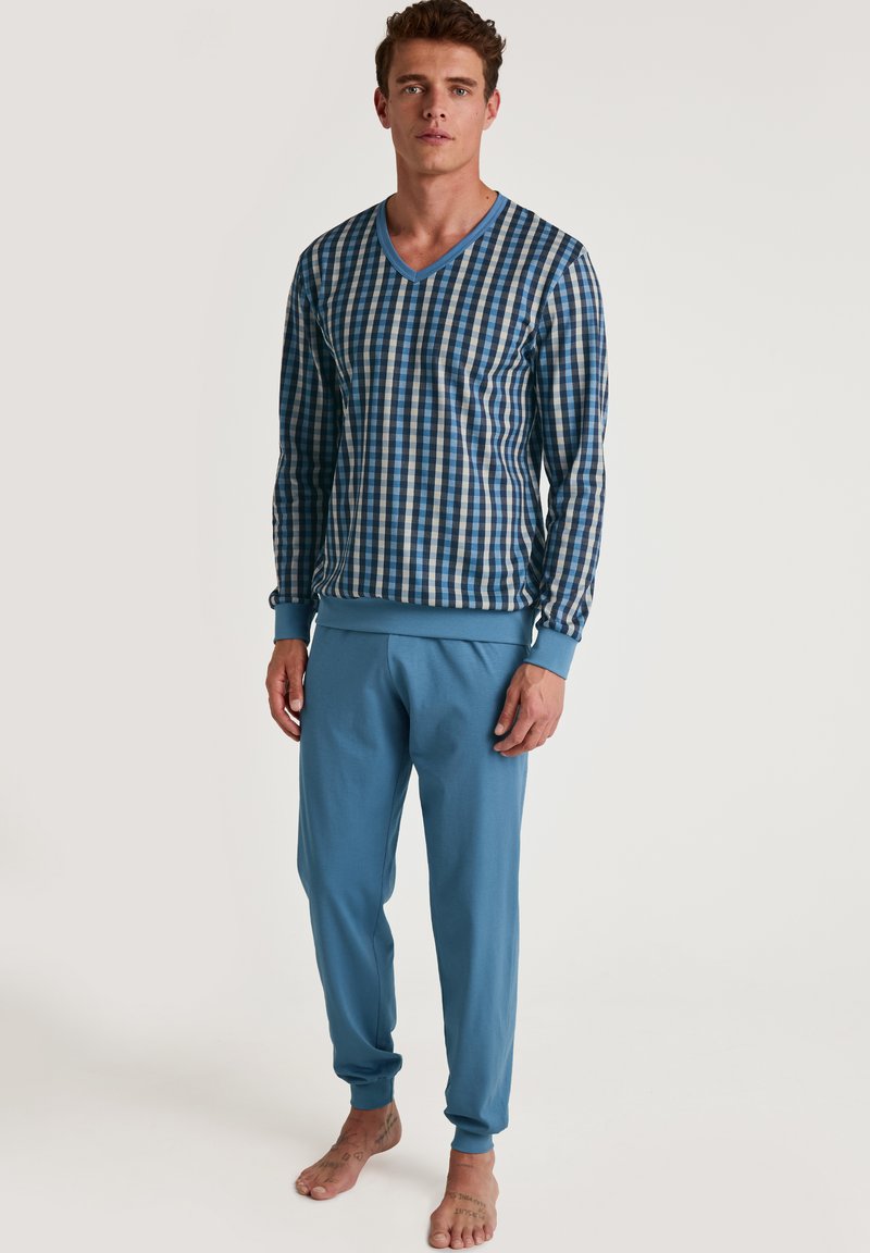 Blauw-wit geruite shirt met lange mouwen en V-hals, gecombineerd met effen blauwe joggingbroek; katoenen stof, relaxte pasvorm, ribgebreide boorden bij de polsen en enkels.