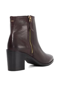 Brown leather ankle boot with a side zipper, block heel, and stitched details. Smooth texture and polished finish enhance its design.