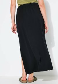Zwarte katoen maxi rok met een elastische tailleband en een zijsplit. De stof is soepel en vloeiend, wat zorgt voor een comfortabele pasvorm.