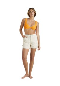 Orange ribbad bikiniöverdel och krämfärgade bomullsshorts med framfickor, som har knappstängning och en skräddarsydd passform.