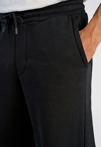 Zwarte joggingbroek gemaakt van een katoenmix, voorzien van zijzakken en een elastische tailleband met een trekkoord voor een verstelbare pasvorm.