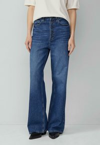 Hoge taille, uitlopende blauwe spijkerbroek met een vijfknopen-front, gemaakt van denim stof met subtiele textuur en een klassieke wassing.