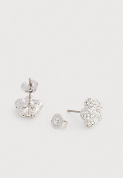 Strieborné náušnice s prstencovým dizajnom a textúrou v tvare kvetu. Jedna náušnica je zdobená čírymi krištáľmi, čo zvýrazňuje detaily.