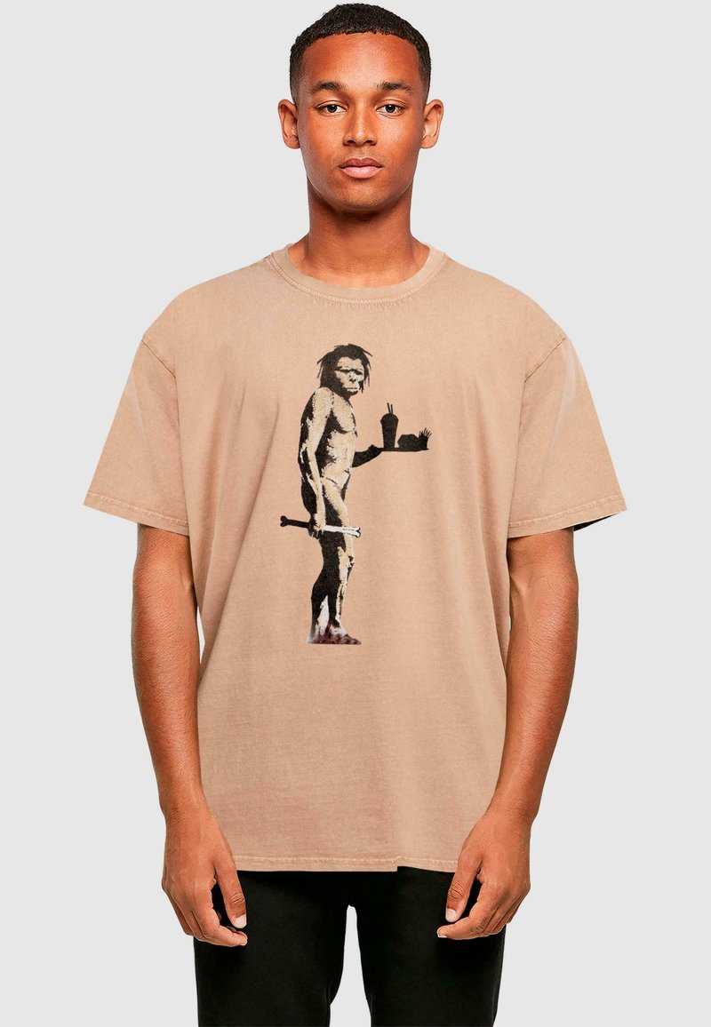 Beige Baumwoll-T-Shirt mit einem Grafikmotiv eines Steinzeitmenschen, der ein Tablett mit Essen und einem Getränk hält, mit Rundhalsausschnitt und lockerer Passform.