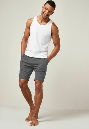 Valkoinen hihanlessa paita ja harmaat shortsit, pehmeä kangas, sivutaskut, huomaamaton oranssi logo shortseissa, istuva muotoilu, käytetään paljain jaloin.