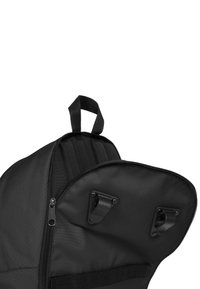 Mochila negra con forma redondeada; cuenta con un cierre de cremallera, clips externos y una tela texturizada. Incluye un asa superior para llevarla.