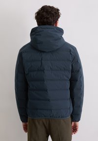 Donkerblauwe donsjas met doorgestikt ontwerp en een aansluitende capuchon. Zachte, gladde textuur, voorzien van elastische manchetten en een licht afgeknipte zoom.