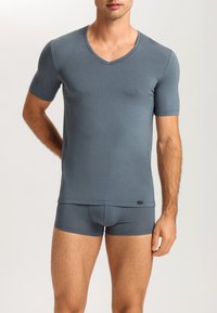 Grå t-shirt med v-hals och korta ärmar, tillsammans med matchande boxerkalsonger. Slät yta, figursydd design och sömlös konstruktion.