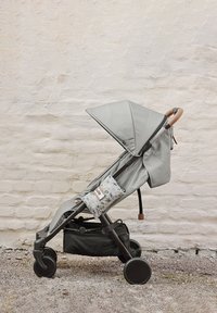 Vaunu vaaleanharmaana, jossa on kuviollinen sivupussi, ruskea kahva ja musta säilytyskori. Varustettu taitettavalla katoksella ja sileillä renkailla.