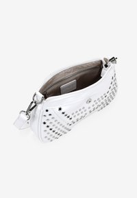 Bolso de mano de cuero blanco con tachuelas plateadas, cierre de cremallera y un interior forrado de tela con un bolsillo adicional con cremallera.