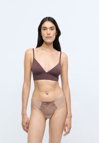 Brown bralette with thin straps and a deep V-neck; matching beige bikini bottom with lace detailing and textured accents.