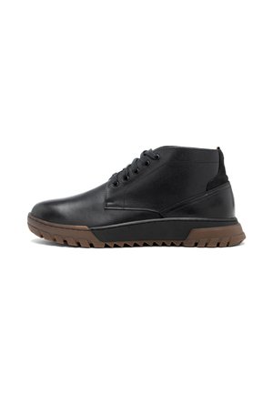 Botas de tobillo de cuero negro con punta redonda, parte superior texturizada, seis ojales y una suela de goma marrón con profundos surcos para tracción.