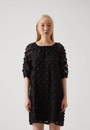 Black dress with sheer fabric, featuring a textured design of raised circular dots. It has a wide neckline and three-quarter sleeves.