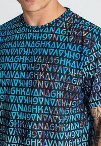 Tričko s krátkým rukávem v modré a černé barvě, s výrazným vrstveným textovým vzorem různých velikostí a hladkou, lehkou texturou látky.